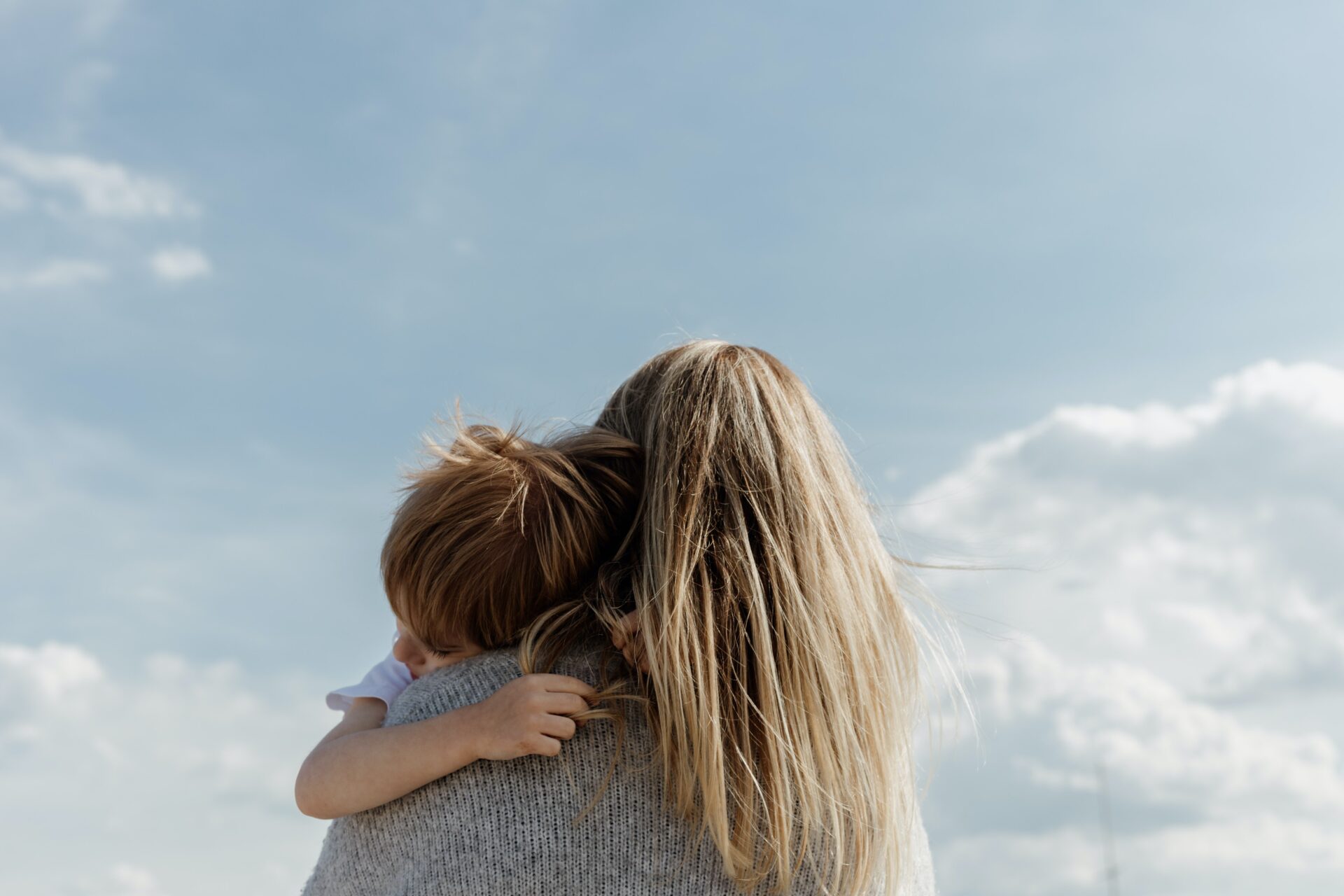 Women Hugs Child With Bule Sky in the Background